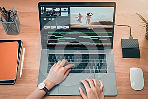 Concept of simple operation of blogger and vlogger, hand using laptop on video editor works with footage on wooden table.
