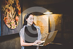 The concept of small business and technology. Young beautiful brunette businesswoman in black dress and gray sweater stands in