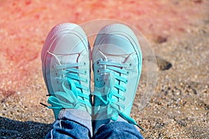 Concept with sneakers on bright sea sand. Sea summer vacation background