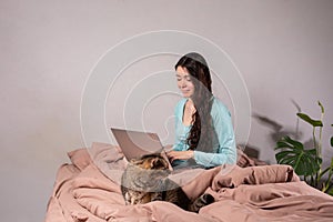 The concept of social distance and isolation. Work from home remotely over the Internet. A young woman works at home on a computer