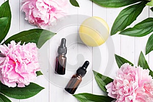 Concept SPA and Wellness. Massage brush, cosmetic oils and soap. Light background with peony flowers.