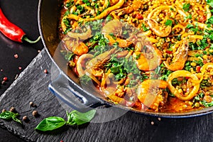 Concept of Spanish cuisine. Paella with seafood, shrimps, squid and greens, cooked in a wok pan on the street. street food