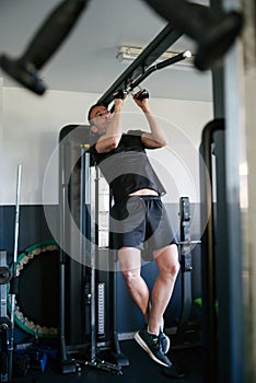 Concept: sport. Athlete man in the gym. Doing pull-ups on the bar