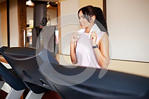 Concept of sport and healthy lifestyle. Young attractive fitness woman running on treadmill, wearing in white sportswear