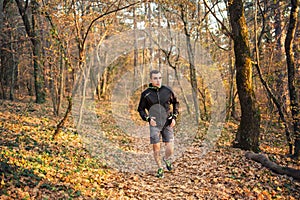 The concept of sport and a healthy lifestyle. A young slender man in sports clothes is engaged in Jogging in the autumn forest or