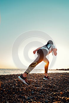 The concept of sport and running. A woman in sportswear at a low start for a run. Rear and bottom view. In the background, the sky