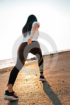 The concept of sport and running. A woman in sportswear at a low start for a run. Rear and bottom view. In the background, the sky