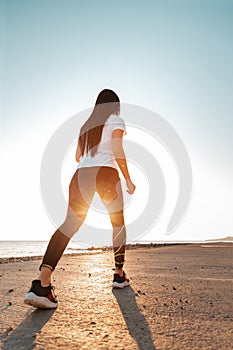 The concept of sport and running. Woman in sportswear at the start for a run. Rear and bottom view. In the background, the sky and