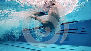 Concept of sports activity, determination, workout, healthy lifestyle. Athlete swims breaststroke. Underwater view