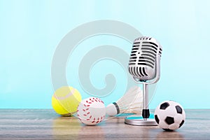 Concept sports commentator : The retro microphone put on the wooden table with football or soccer , tennis ball , baseball and photo
