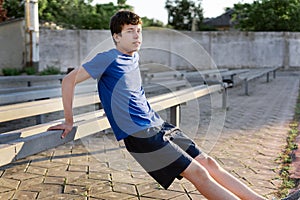 Concept of sports and health - teen boy training and pushups at the stadium. Physical exercise. Workout, fitness and health care