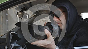 The concept spy or private detective takes photos with a long-focus lens from the car window.