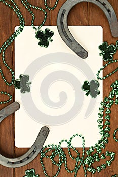 Concept of St. Patrick. green clover necklaces and lucky horseshoes with poker cards on wooden background, top view
