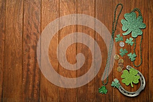 Concept of St. Patrick. Green necklaces and clovers, horseshoes and lucky coins on wooden background.