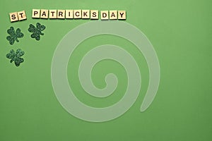 Concept of St. Patrick.Wooden letters making the phrase Happy saint Patricks day and green clovers on a green background