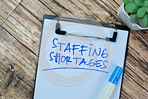 Concept of Staffing Shortages write on paperwork isolated on Wooden Table