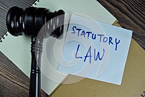 Concept of Statutory Law write on sticky notes with gavel isolated on Wooden Table