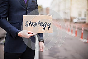 The concept of strategy. A young businessman in a business suit holds a sign in his hand