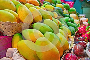 Concept street trade exotic fruits. Tropical fruits on counter of a street shop. Ripe yellow mango and dragon fruit.