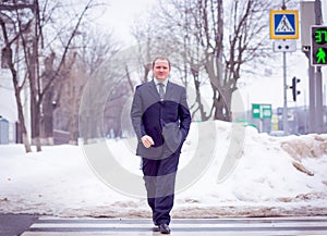 The concept of success and life path. A confident man in a business suit crosses the road to the green light in winter when it`s