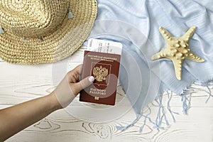 The concept of summer holidays. A hat, a female hand holds a passport of the Russian Federation, a starfish and a blue