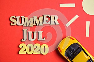 The concept of summer - July in the new year. Wooden numbers 2020 with letters and abstract sun, car on a red background. Top view