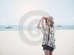 The concept of summer vacation at the beach. Happy Asian woman wearing a hat relaxing at the seaside and looking out in the summer