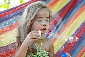 Concept summer, vacation, weekend- beautiful blond-haired girl with blue eyes is lying on a bright hammock with rainbow colors