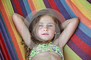 Concept summer, vacation, weekend- beautiful blond-haired girl with blue eyes is lying on a bright hammock with rainbow colors