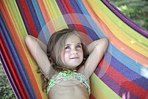 Concept summer, vacation, weekend- beautiful blond-haired girl with blue eyes is lying on a bright hammock with rainbow colors