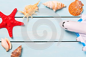 Concept of summer and vacations. Sea shells with toy plane and starfish or light blue wooden table. Free space for your text