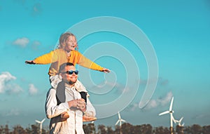 The concept of sustainable resources and renewable energy. Father and child girl on wind turbines farm. People in the