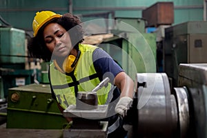 Concept of technician heavy industry, Woman African American engineer wear hardhat working at machine in factory.