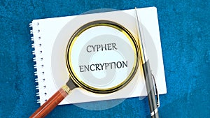 The concept of technology and development. The CYPHER ENCRYPTION concept phrase in a clean notebook through a magnifying photo