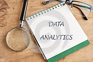 The concept of technology and development. Phrase, words, text DATA ANALYTICS in a notebook on an old background, in a