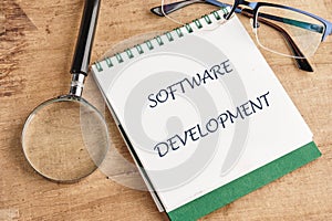 The concept of technology and development. Phrase, words, text SOFTWARE DEVELOPMENT in a notebook on an old background, in a