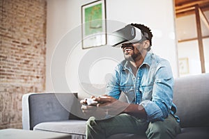 Concept of technology,gaming,entertainment and people.Happy african man enjoying virtual reality glasses while relaxing