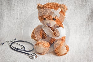 Concept teddy bear childhood diseases at textile background