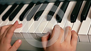 Concept on the theme of a child playing a musical instrument. Close-up of children`s hands playing the keys of a piano, learning t