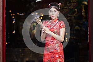 Concept to celebrate Chinese New Year, Vegetarian Festival : Chinese woman in a red cheongsam dress holding incense pay homage to