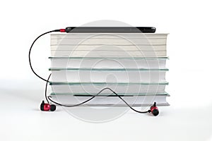 Concept to listen to audio books. Red headphones near stack of books. White background with copy space for text