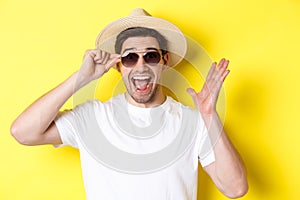 Concept of tourism and holidays. Close-up of surprised man shouting for joy, enjoying vacation, wearing sunglasses with
