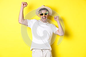 Concept of tourism and lifestyle. Happy lucky guy winning trip, rejoicing and wearing holiday outfit, summer hat and