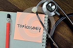Concept of Toxicology write on sticky notes with stethoscope isolated on Wooden Table