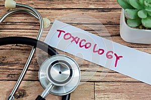 Concept of Toxicology write on sticky notes with stethoscope isolated on Wooden Table photo