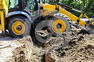 Concept of the tractor, the tractor digs and buries a trench for laying water on a forest plot for the construction of the house.