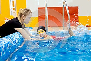 Concept training swimming child. Little kid girl with glasses learning to swim