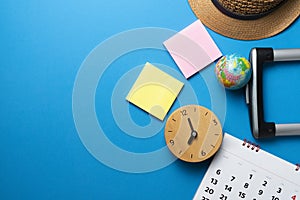 Concept of travel, clock, suitcase, hat and accessories vacation trip and long summer weekend planning on blue table background