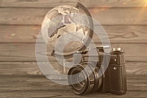 Concept travel, globe and vintage camera on a wooden background.