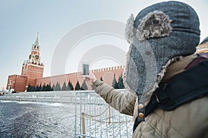 Concept of travel. The tourist in a cap makes photos on his phone Moscow landscape with the Kremlin Intercession Cathedral on Red